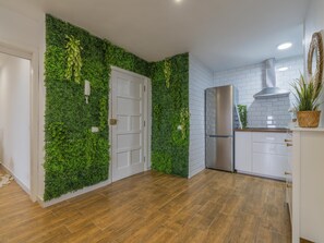 Eine moderne Küche mit grüner Wand, weißen Schränken, einem Edelstahlkühlschrank und Holzboden.