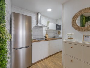 Eine moderne Küche mit weißen Schränken, einem Edelstahlkühlschrank, einer eingebauten Mikrowelle und einer Holz Arbeitsplatte.