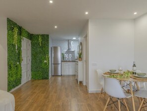A modern kitchen with white cabinets, a stainless steel refrigerator, and a green vertical garden wall. - CHL La Palma Beach Infront of the sea (Santa Cruz de la Palma)