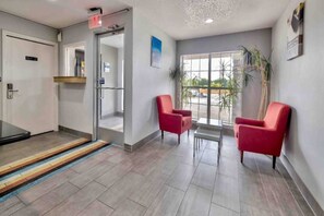 A reception area with a glass door entrance, a small table with chairs, and a view of the outdoors through large windows. - 1 Queen Bed | Smoking, Kitchen (Dallas)