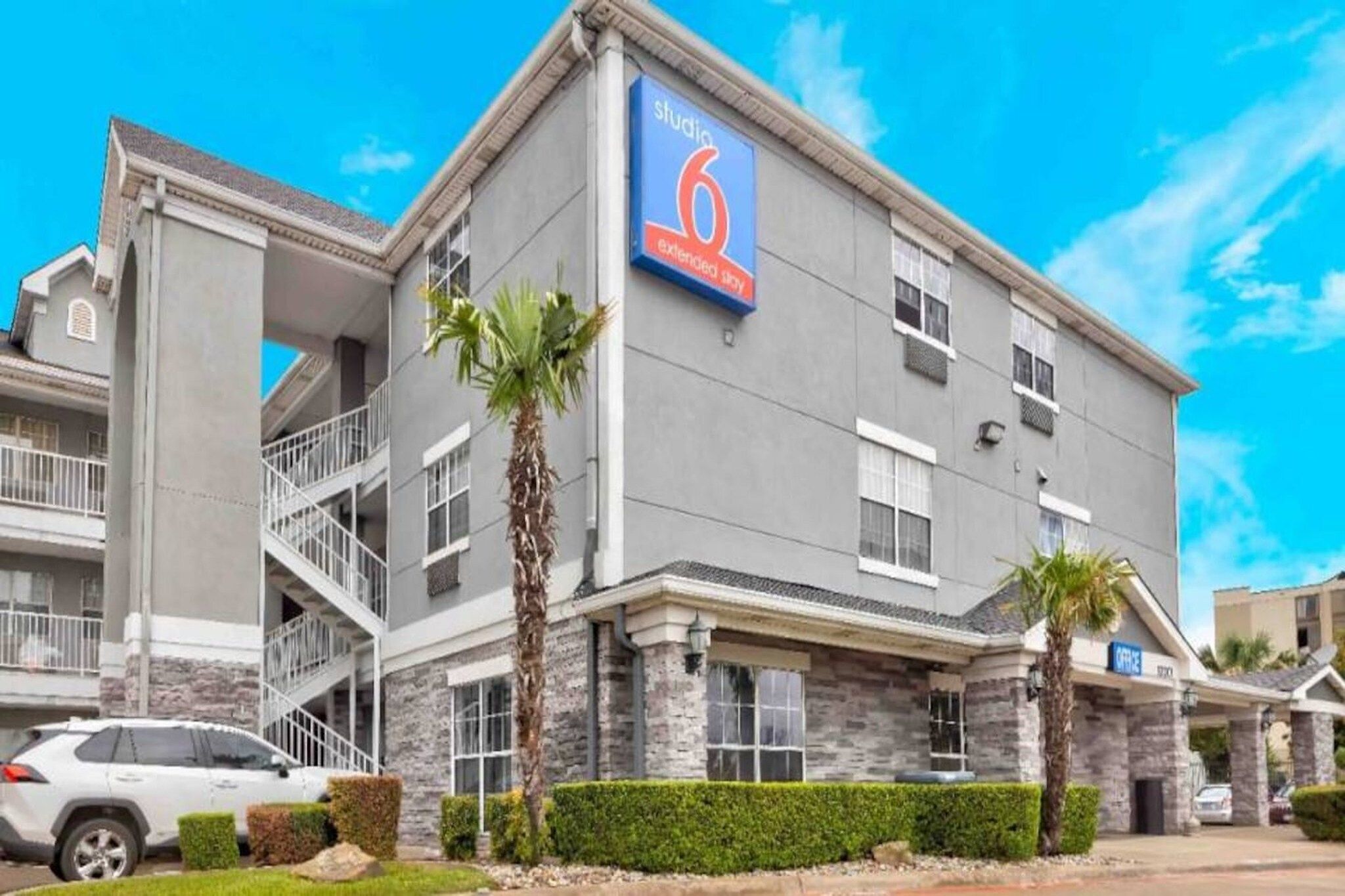 A multi-story hotel with a prominent '6 extended stay' sign, a covered outdoor area, and a parking lot.