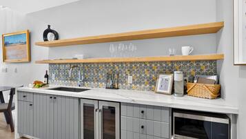 A modern kitchen with a built-in oven, a wine bottle, and a fruit bowl on the counter.