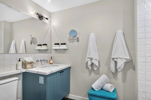 A bathroom with a white sink, a mirror, a towel rack, and a blue cabinet. - Cal King Studio | Paso Market | Walk to City Park + Fairgrounds | The Tulip Tree (Paso Robles)