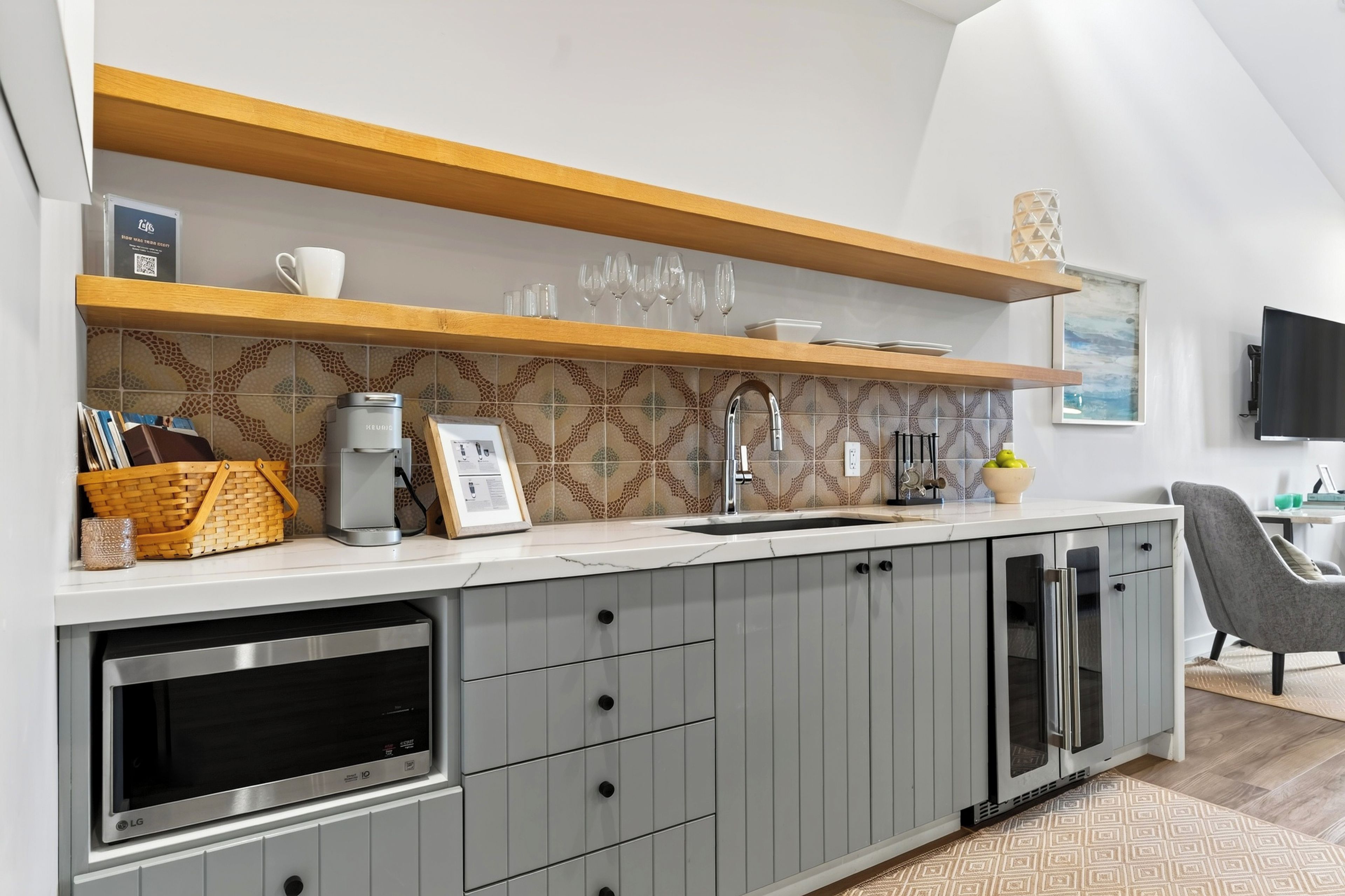 A modern kitchen with grey cabinets, a built-in oven, a microwave, and a sink.