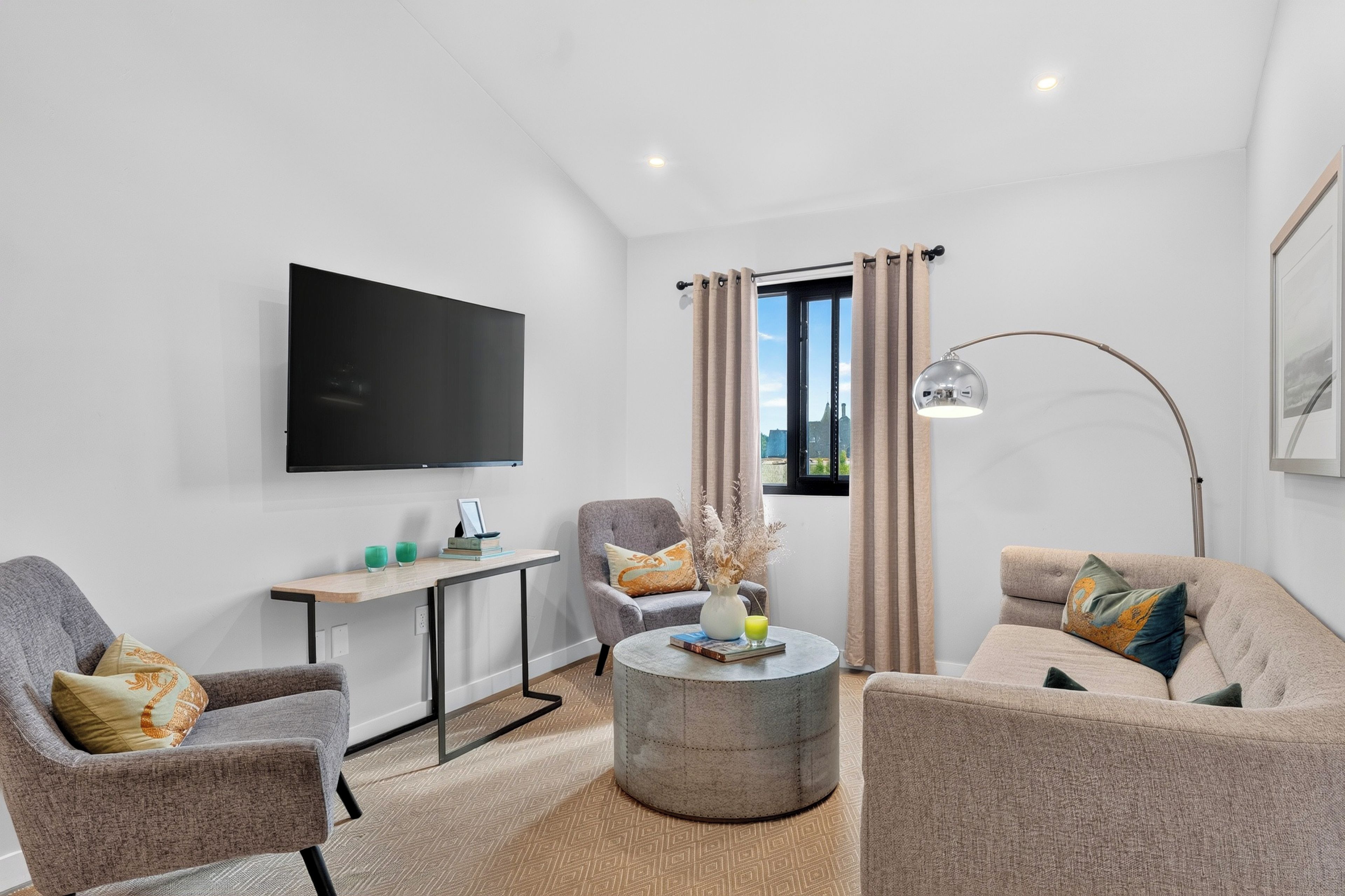 Settle into the bright lounge, where a comfortable sofa, soft seating, and wall-mounted TV make it easy to unwind.