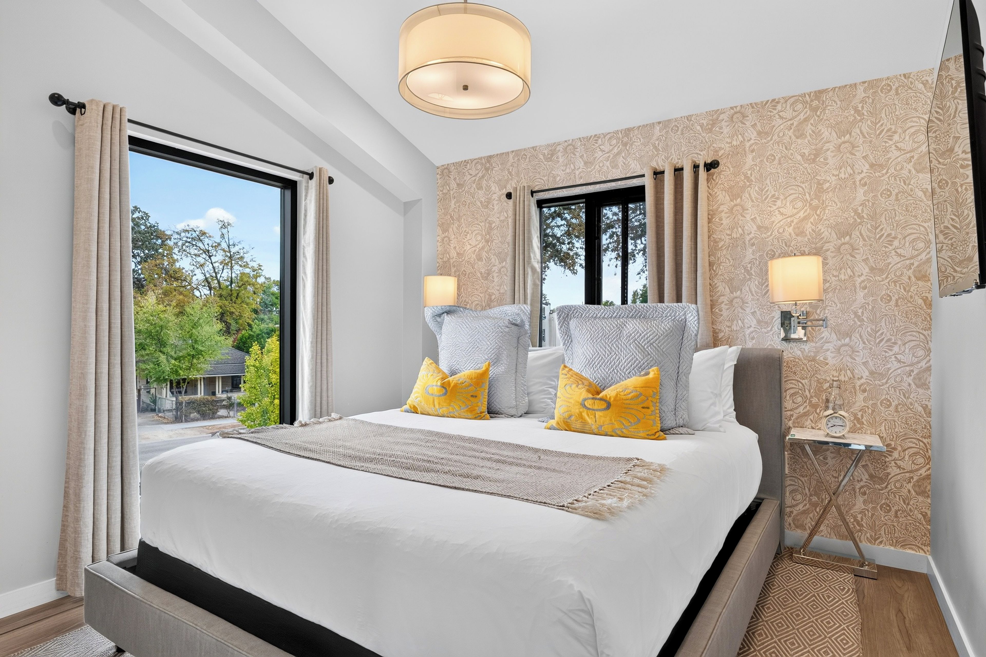 Bedroom 1: Rest easy in the king bed beneath a patterned accent wall, with soft textures and natural light.