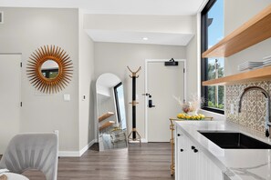 A modern kitchen with a large window, a sunburst mirror, and a white countertop. - Paso Market Walk + Wine Country | Near Downtown & Event Center | The Oak Room (Paso Robles)
