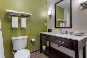 Un baño con inodoro, lavamanos, espejo y toallero.