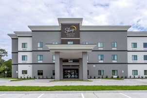Un hotel Sleep Inn & Suites con un diseño moderno, que cuenta con una entrada destacada y un cielo despejado.