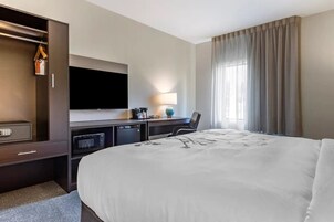 Habitación de hotel con una cama grande, un televisor de pantalla plana en la pared, un escritorio con lámpara, microondas y armario.