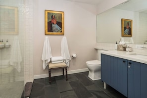 A bathroom with a shower, a toilet, a sink with a mirror, and two towels on a chair. - Paso Market Walk Studio • Walk To Downtown + Tasting Rooms | The Fig (Paso Robles)