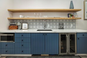 A modern kitchen with a built-in microwave, a sink, and blue cabinets. - Paso Market Walk Studio • Walk To Downtown + Tasting Rooms | The Fig (Paso Robles)