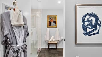 A bathroom with a shower, a towel rack, and a framed painting on the wall.