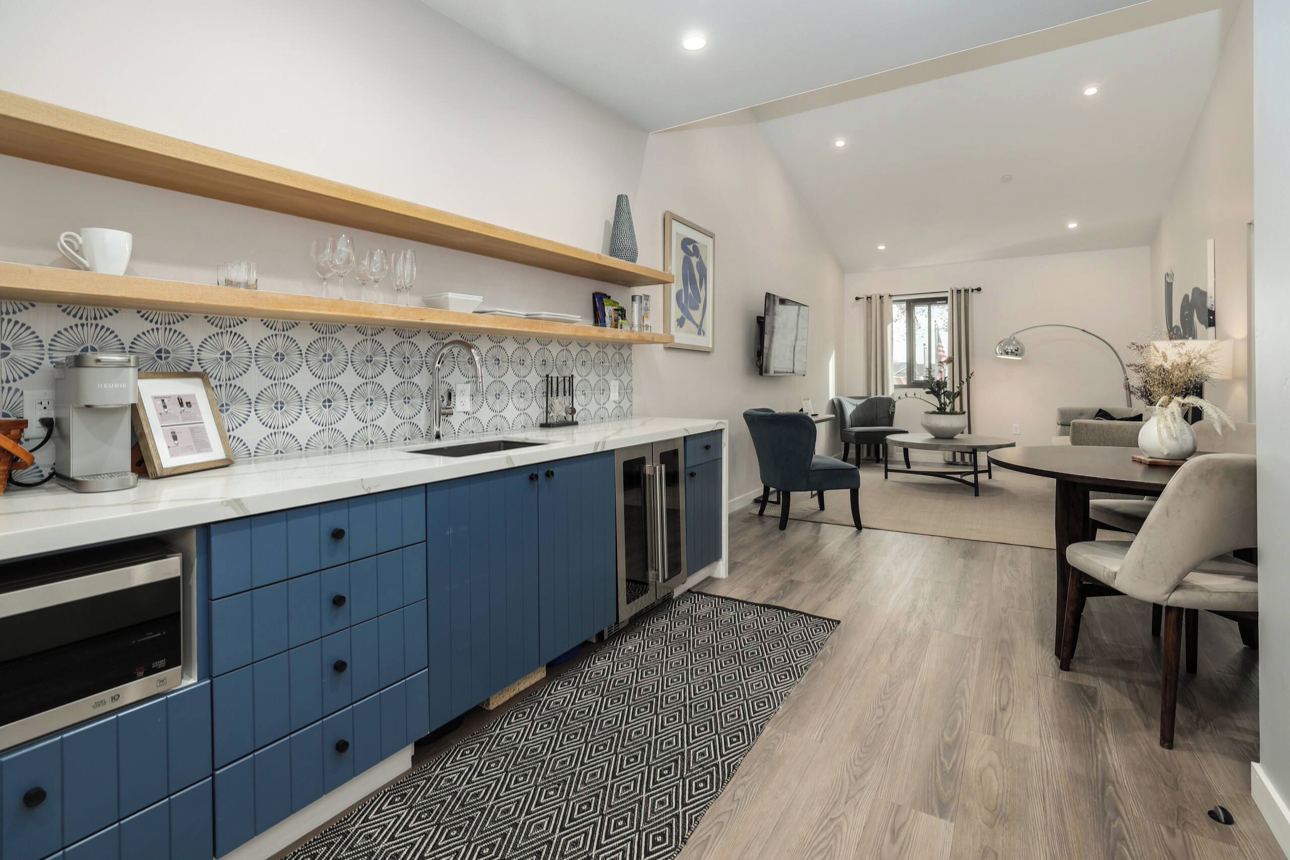 A modern kitchen with blue cabinets, a white countertop, and a patterned backsplash.