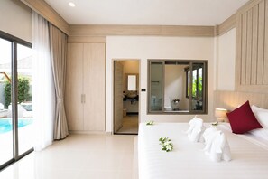 Habitación de hotel con una cama grande, baño y vistas a una piscina.