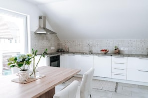Eine moderne Küche mit weißen Schränken, einer Holz Arbeitsplatte und einer Edelstahl-Dunstabzugshaube.