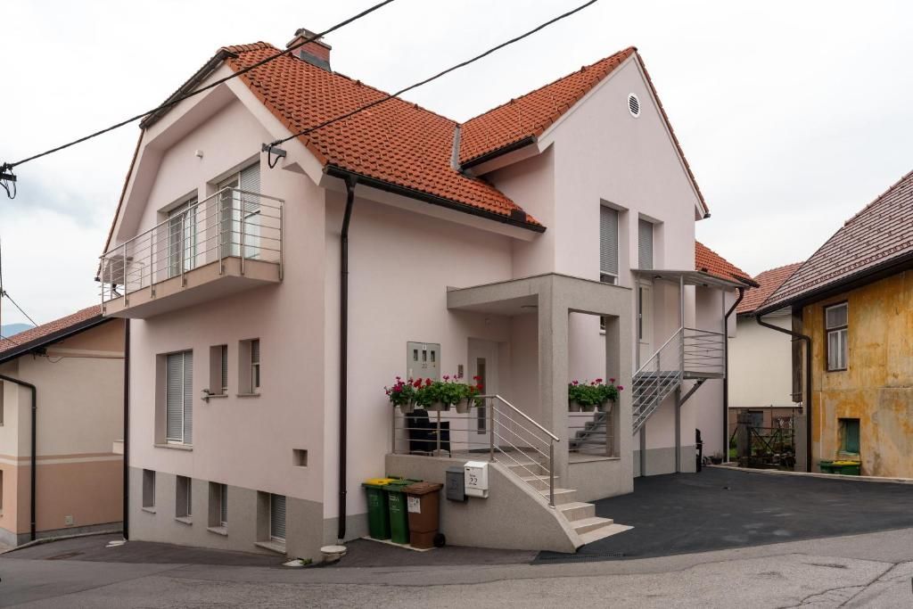 Un immeuble résidentiel de deux étages doté d’un balcon, d’un escalier et d’un petit jardin à l’avant.