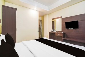 Una habitación de hotel con una cama, una mesita de noche, un espejo y un televisor.