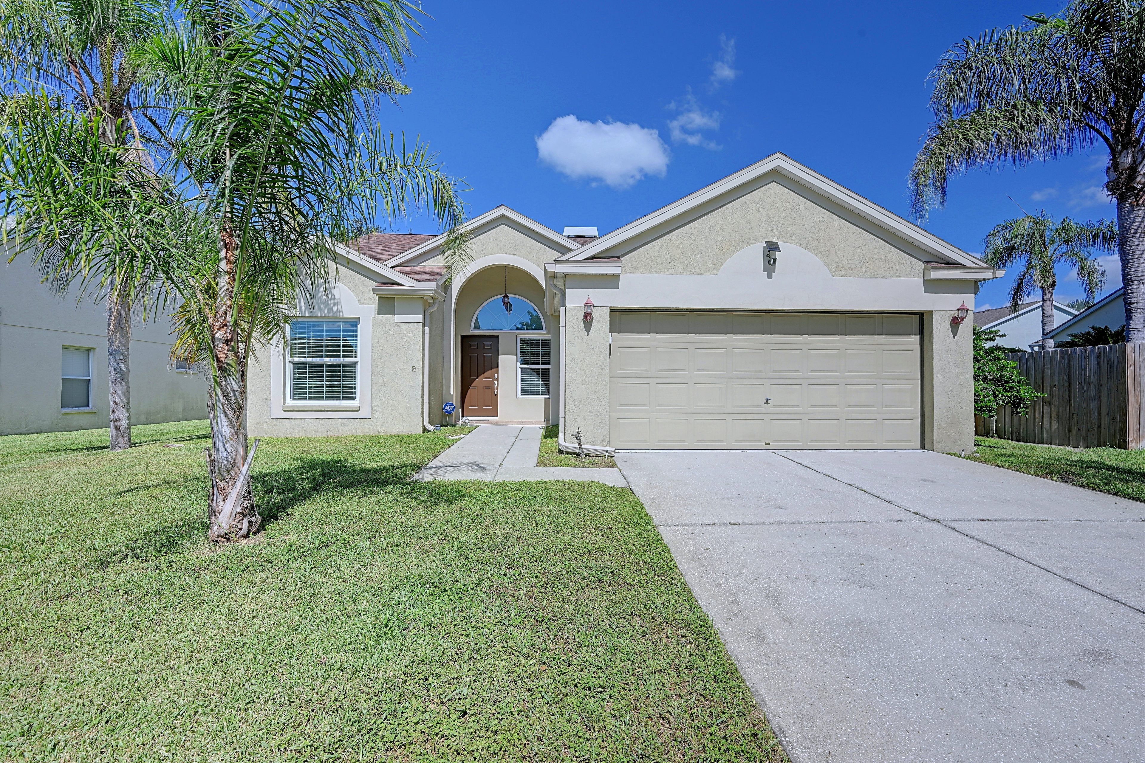 A residential house with a garage, a front entrance, and a lawn.
