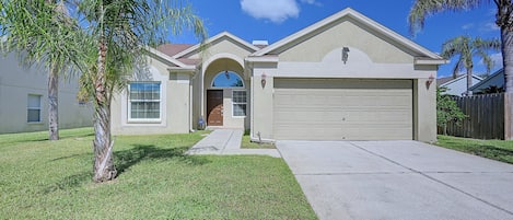 A residential house with a garage, a front entrance, and a lawn.