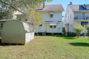 A residential area with a two-story house, a small shed, and a grassy yard.