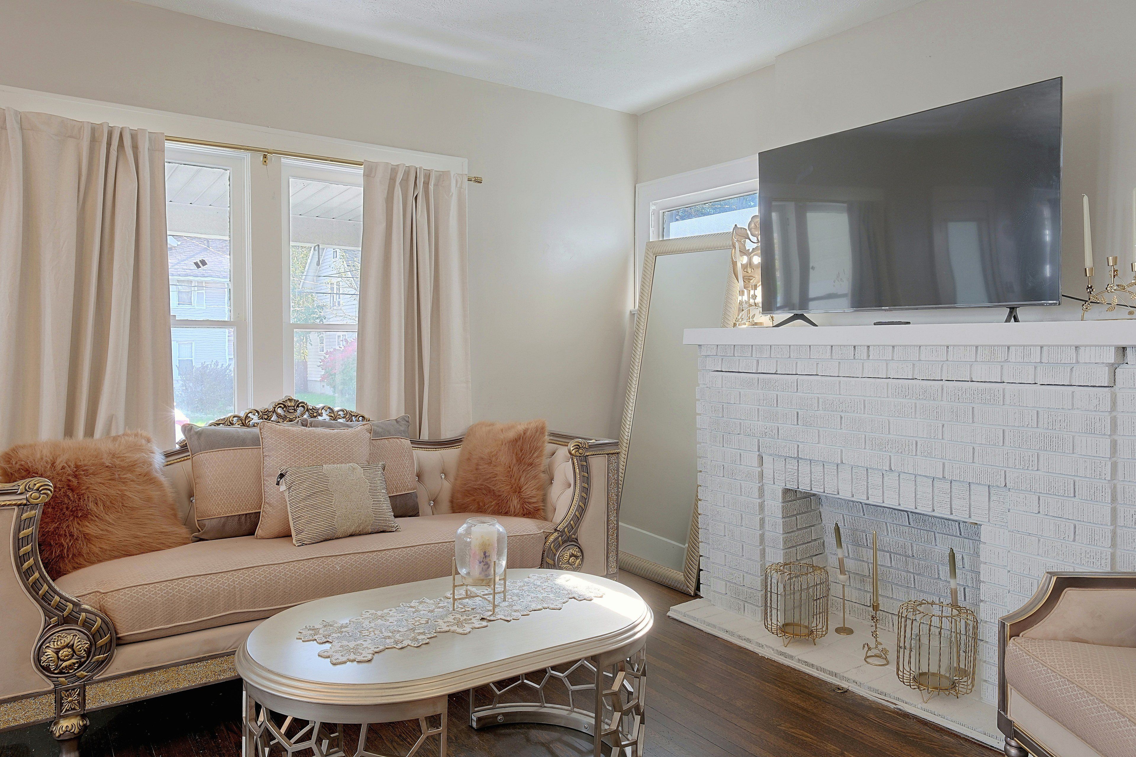 A living room with a sofa, a television, and a fireplace with a brick wall.