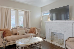 A living room with a sofa, a television, and a fireplace with a brick wall.
