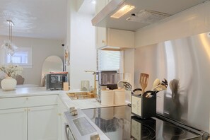 A modern kitchen with a built-in oven, a coffee machine, and a glass-top dining table.