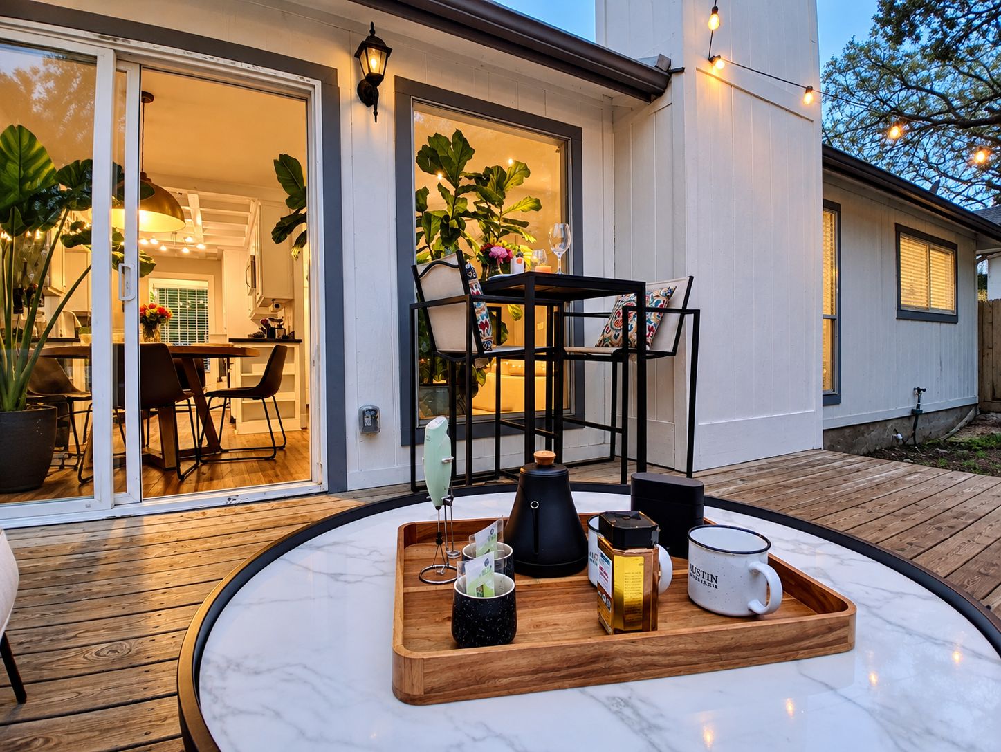 A modern outdoor seating area with a wooden table, chairs, and a tray with coffee and a mug.
