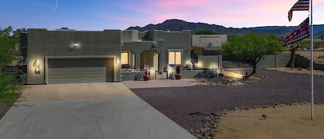 A modern house with a garage, a driveway, and a flagpole with an American flag.
