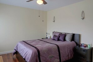A bedroom with a bed, a nightstand, a wall clock, and a ceiling fan. - 4 Mi to Main Street! Huntington Beach Condo (Huntington Beach)