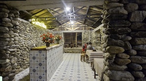 A rustic interior with stone walls, a tiled floor, and a central counter with flowers. - Osima Villas Mu Cang Chai (Pung Luong)