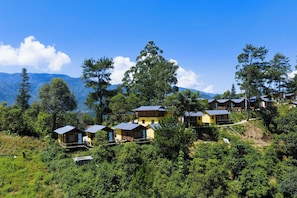 A cluster of wooden cabins with metal roofs, surrounded by lush greenery and mountains in the background. - Osima Villas Mu Cang Chai (Pung Luong)