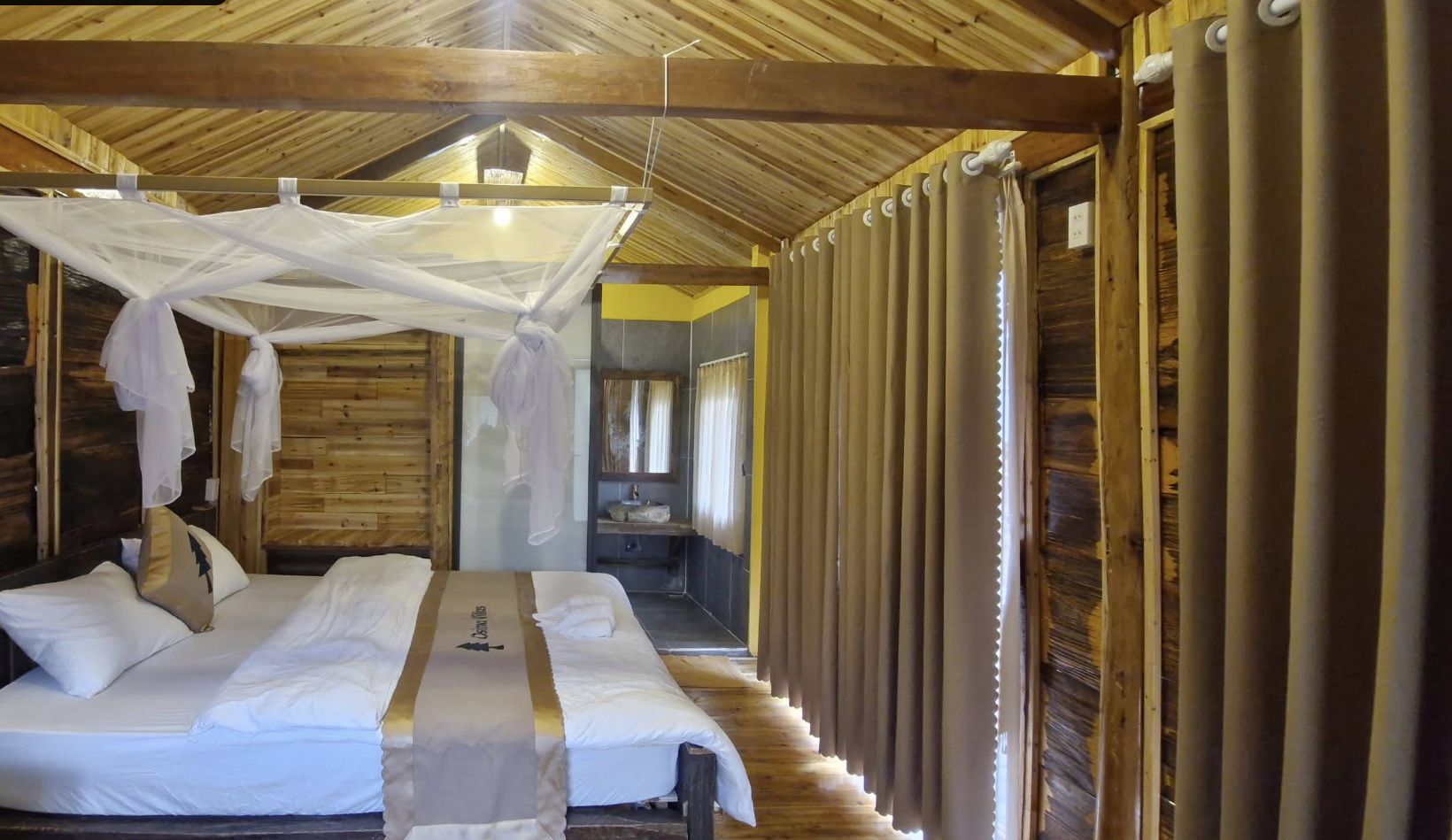 Una habitación con cama, dosel y baño con lavamanos y espejo.