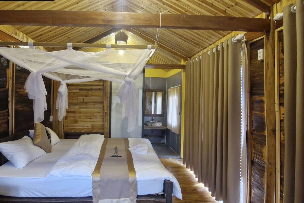 A room with a bed, a canopy, and a bathroom with a sink and mirror.