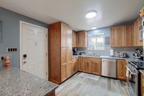 A kitchen with wooden cabinets, a stainless steel dishwasher, a stove, and a window with a view. - Gateway to Zion NP! Home 1 Mi to Dtwn Cedar City (Cedar City)