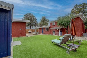 Ein Wohnhof mit Rasen, einem Patio-Tisch und Liegestühlen.