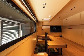 A modern interior with a long bench, a television, and a window with blinds. - X Hotel (Tongzhou)