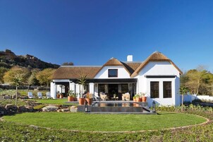 Una casa moderna con un amplio jardín delantero, piscina y zona de patio.