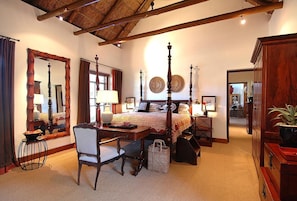 Une chambre à coucher avec un lit à baldaquin, un bureau, une chaise et une armoire.
