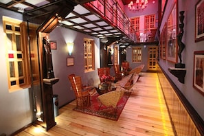 A hotel lobby with a wooden floor, wicker chairs, a red rug, and a staircase with a red railing. - Hotel Parque Mexico - Petit (Mexico City)