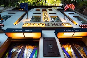 Exterior de El Parque Mexico, con señalización iluminada y banderas.