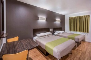 Habitación de hotel con dos camas, una mesa y sillas.