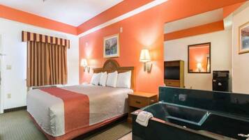 A hotel room with a bed, bedside tables, a desk, a mirror, and a bathroom area.