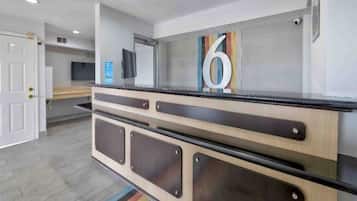 A reception desk with a number '6' sign, a flat-screen TV, and a security camera.