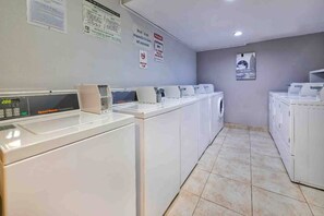 A laundry facility with multiple washing machines and dryers, a digital control panel, and informational posters on the walls. - 2 Queen Beds | Non-Smoking, Kitchen (Dallas)