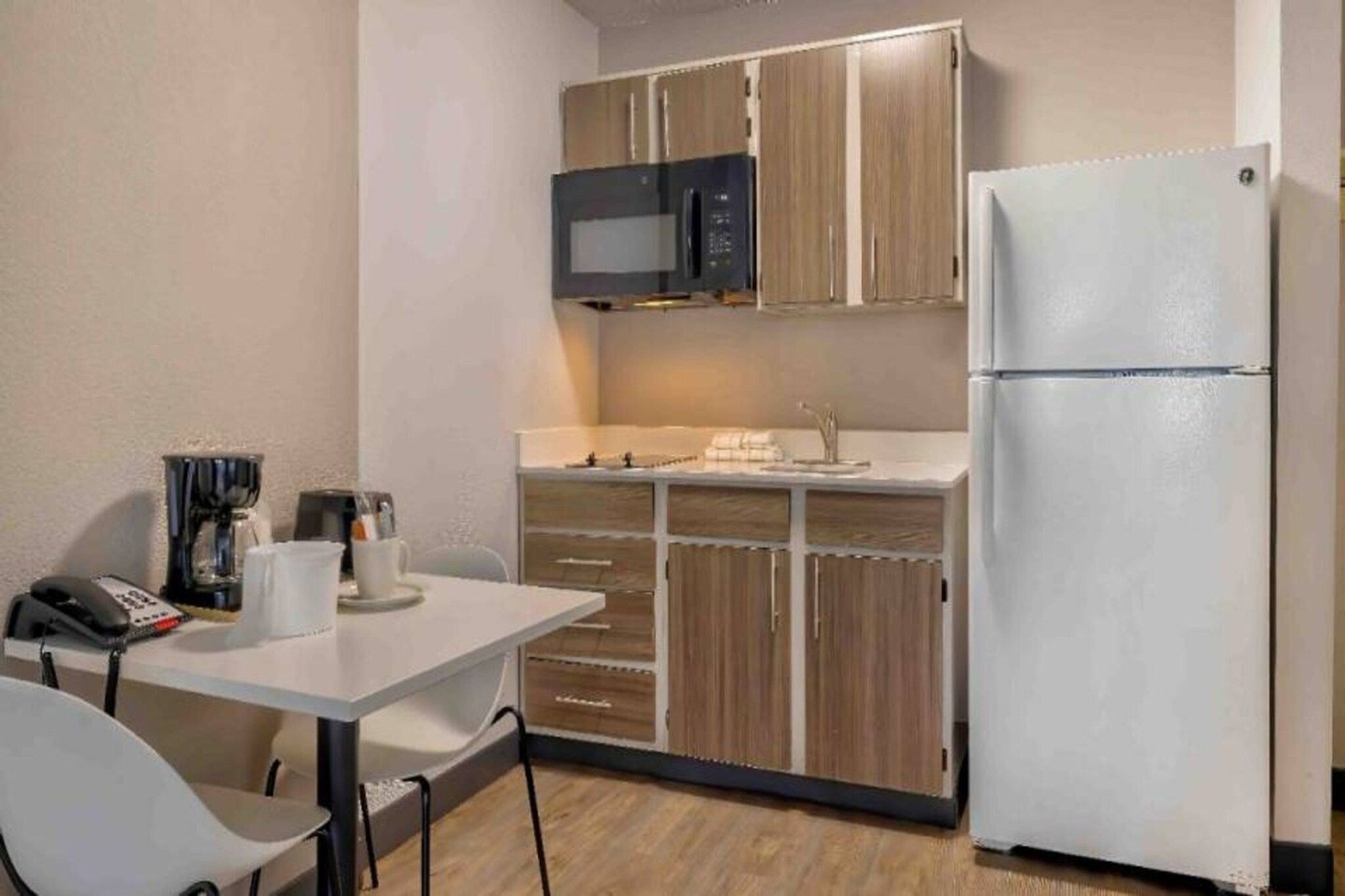 A compact kitchen with a microwave, refrigerator, and a small dining table with chairs.