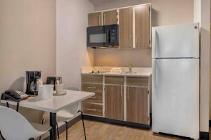 A compact kitchen with a microwave, refrigerator, and a small dining table with chairs. - 2 Queen Beds | Non-Smoking, Kitchen (Dallas)