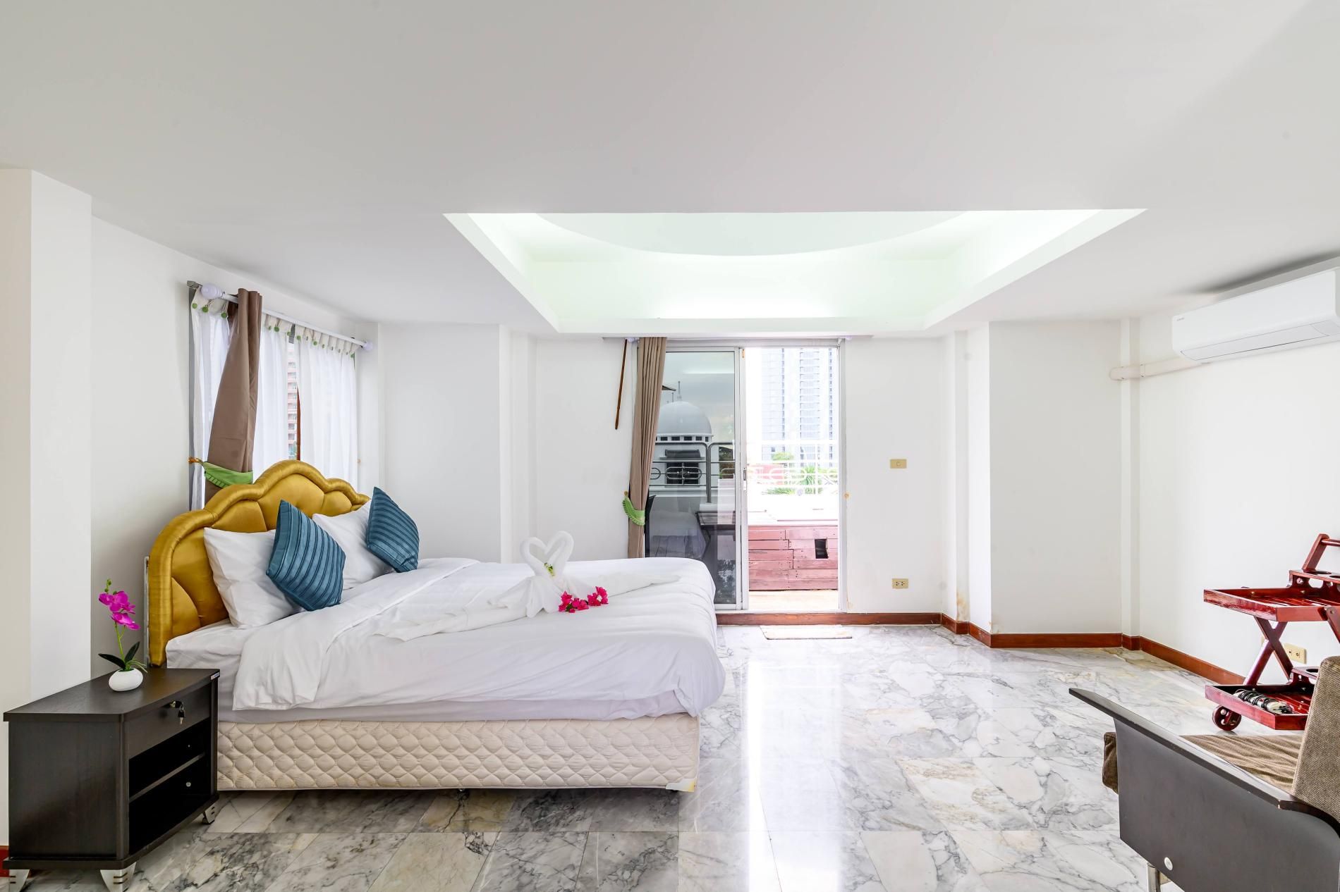 A hotel room with a bed, a nightstand, a desk, and a view of the outside.