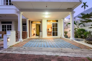 A hotel entrance with a covered porch, a tiled walkway, and a palm tree in the background. - Wongamat 3BR Townhouse near Beach (NP1) (Bang Lamung,)